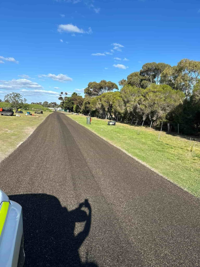A freshly paved road through a grassy rural area